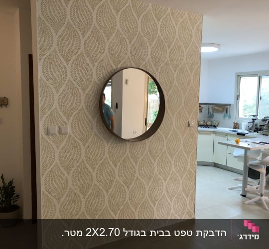קיר עם טפט דוגמת עלים ומראה עגולה